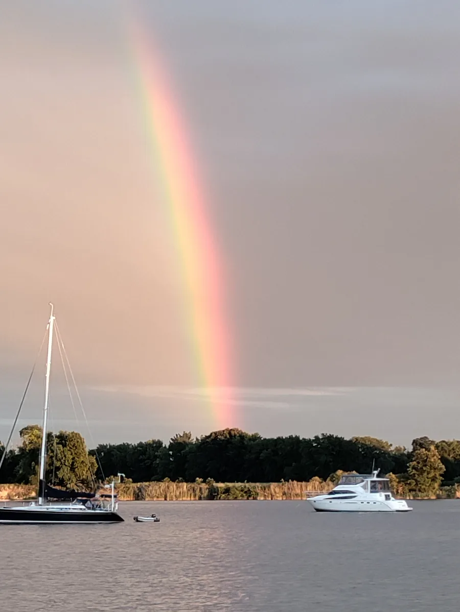A rainbow over calm water beneath a dramatic sky.